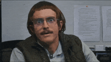 a man wearing glasses and a wig is sitting in front of a paper that says " rules " on it