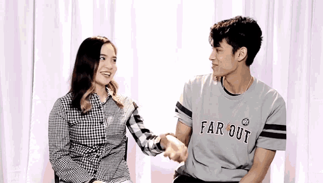 a man wearing a shirt that says far out holds hands with a woman