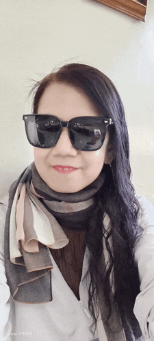 a woman wearing sunglasses and a scarf is taking a selfie on a vivo v15a