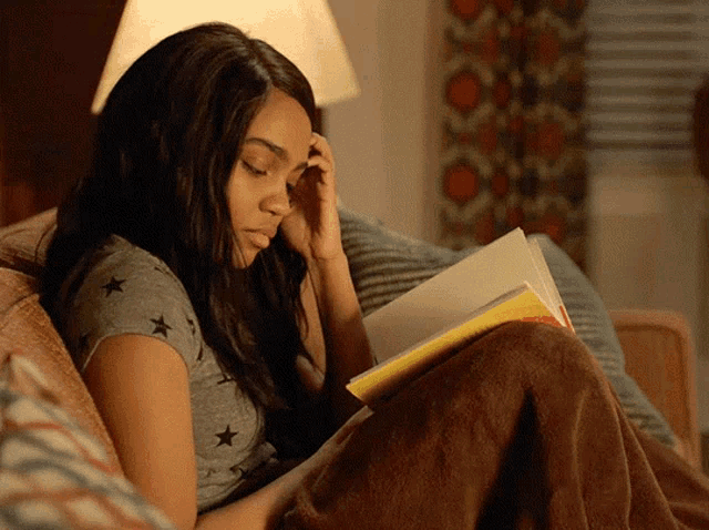 a woman is reading a book while sitting on a couch
