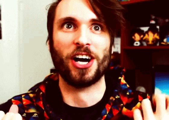a man with a beard is wearing a colorful shirt and making a surprised face