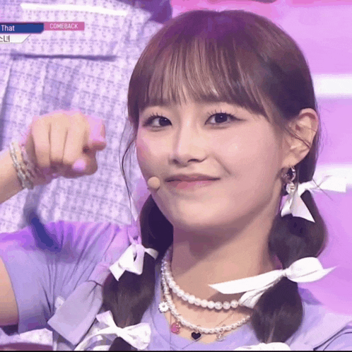 a girl in a purple shirt is pointing at the camera with the words that comeback behind her