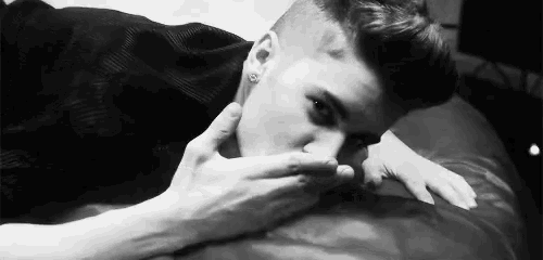a man laying on a bed with his hand on his mouth .
