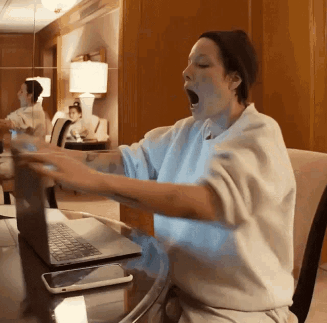 a woman yawning while using a laptop
