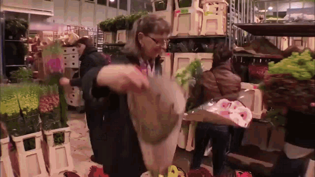 a woman is holding a bag of flowers in front of a sign that says ' flowers ' on it