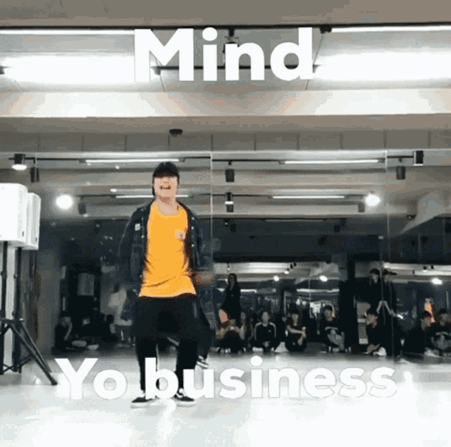 a man is dancing in front of a mirror with the words mind yo business behind him