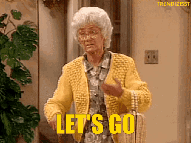an older woman in a yellow sweater is saying let 's go