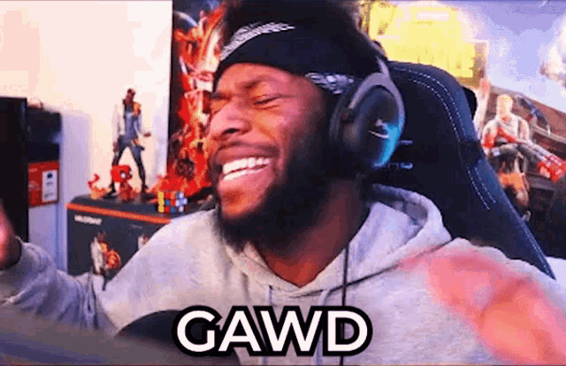 a man wearing headphones and a headband is sitting in a chair and laughing .