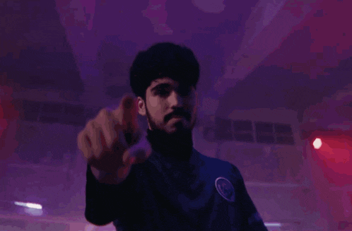 a man with a beard is pointing at the camera in front of a crowd of people