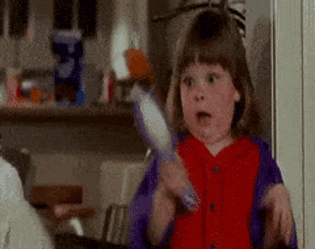 a little girl is holding a toothbrush in her hand .