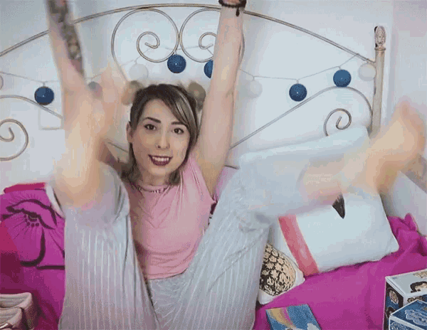 a woman is sitting on a bed with her legs up
