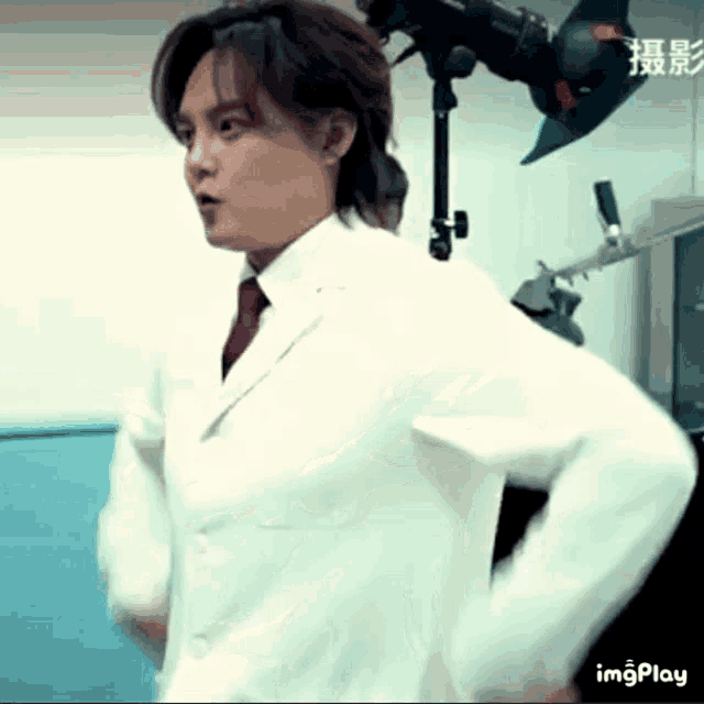 a man in a white coat and tie is standing with his hands on his hips