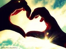 a couple of hands making a heart shape with the sun behind them .