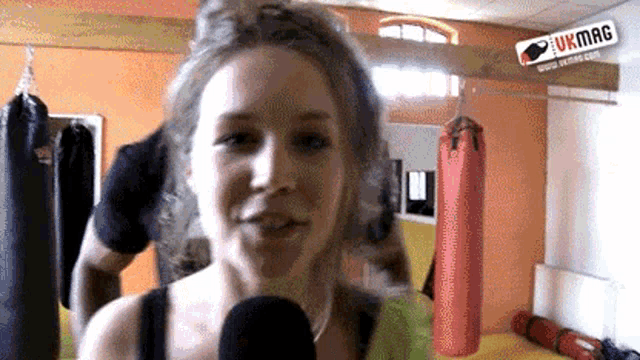 a woman talking into a microphone in front of a ukmag sign