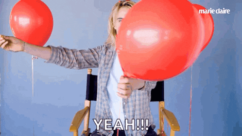 a person holding a red balloon with the word yeah written on it