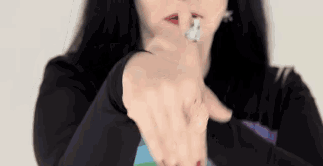 a woman is holding her finger to her mouth and pointing at the camera