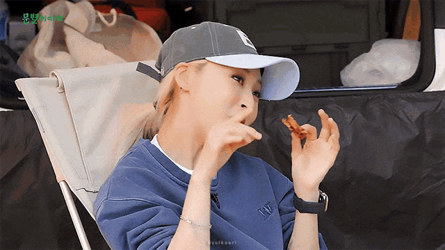 a woman wearing a hat and a sweatshirt with the letter w on it is eating something