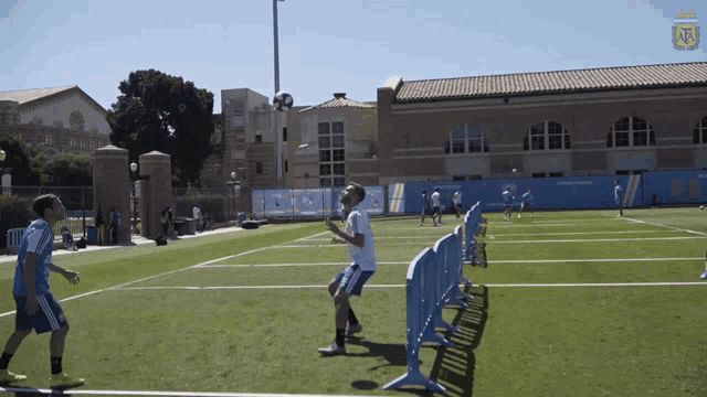 people playing soccer on a field with a building in the background that says ucla
