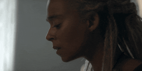 a close up of a woman 's face with dreadlocks on her hair