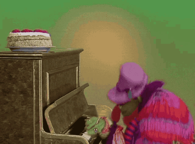 a clown playing a piano with a cake on top of it