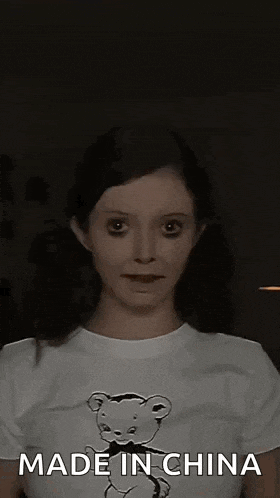 a woman wearing a t-shirt with a teddy bear on it is making a funny face .
