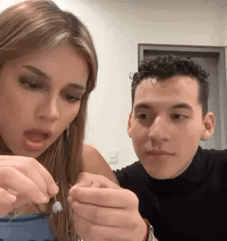 a man and a woman are sitting next to each other in a room looking at something .