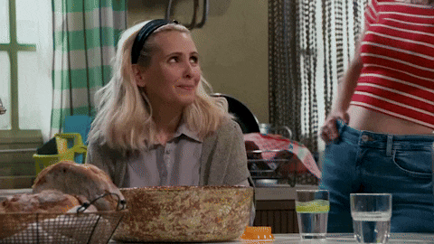 a woman is sitting at a table with a bowl of food and a glass of water