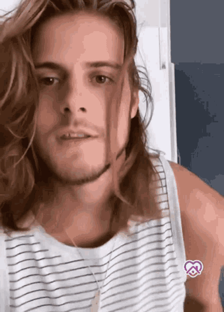 a man with long hair and a beard wearing a striped tank top