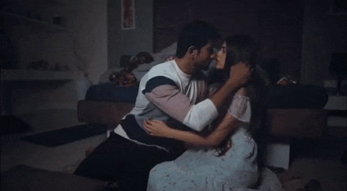 a man and woman are kissing on the floor in a bedroom