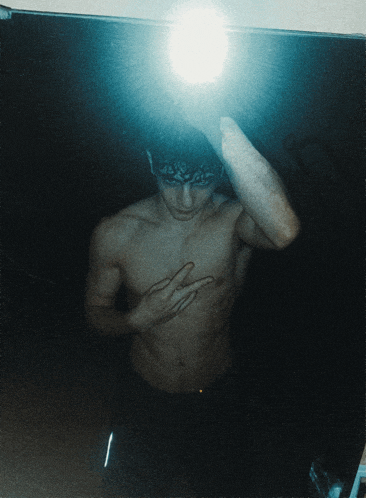 a shirtless man is taking a picture of himself in the mirror