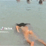 a woman in a bikini is standing on a beach with people in the background