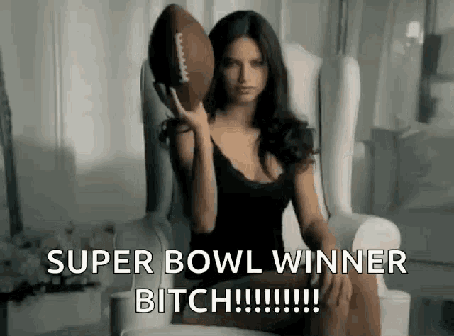 a woman is sitting in a chair holding a football with the caption super bowl winner bitch .