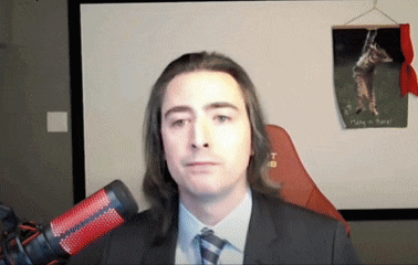 a man in a suit and tie stands in front of a microphone with a picture of a giraffe on the wall behind him
