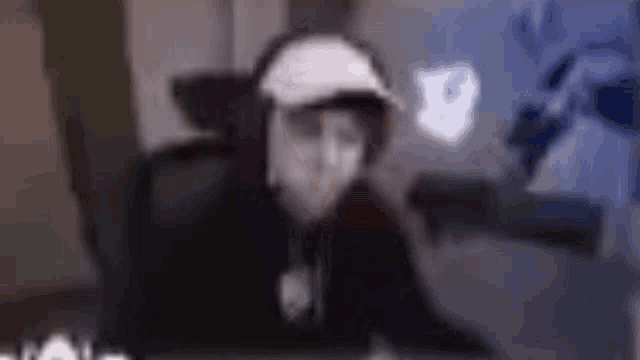a man wearing headphones and a hat is sitting in front of a computer .