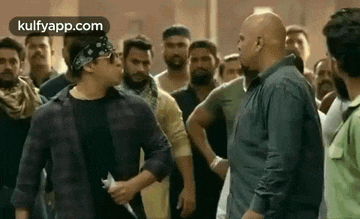 a group of men are standing next to each other in a crowd and talking to each other .