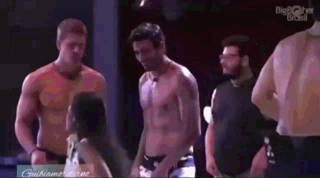 a group of shirtless men are standing next to each other on a stage in front of a big brother brasil logo