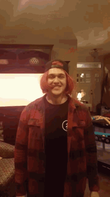 a young man with pink hair is wearing a plaid shirt and a black hat