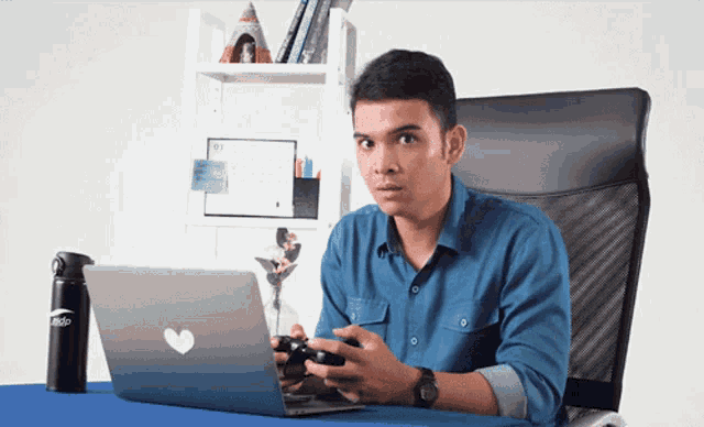a man is playing a video game while sitting in front of a macbook pro