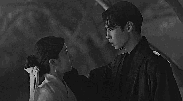 a man and a woman are looking into each other 's eyes in a black and white photo .
