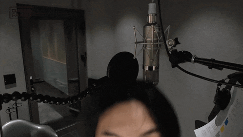 a close up of a person 's face in front of a microphone in a recording studio