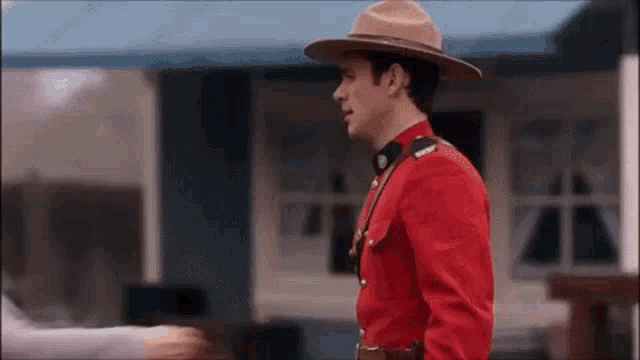 a man in a red uniform and hat is standing next to a woman .