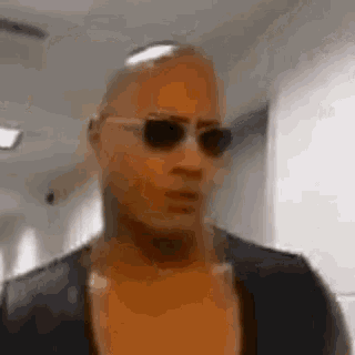 a man wearing sunglasses is walking down a hallway .