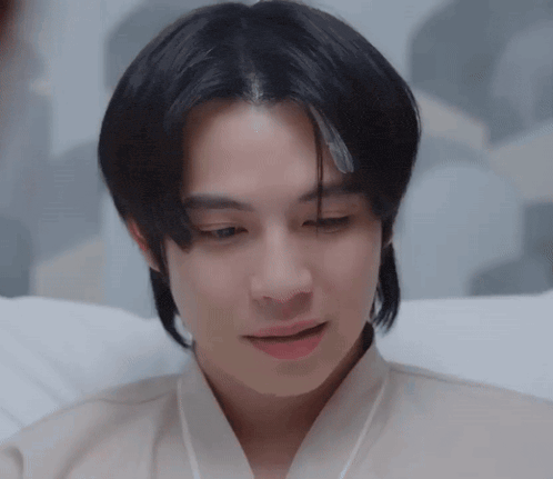 a young man with long black hair is laying in a hospital bed