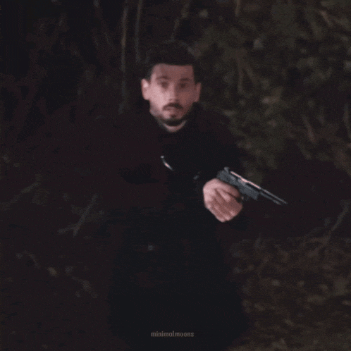 a man in a black coat is holding a gun in a blurry photo by minimalmoons