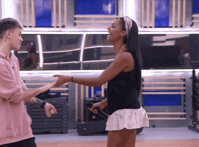 a man in a pink hoodie and a woman in a white skirt are dancing together