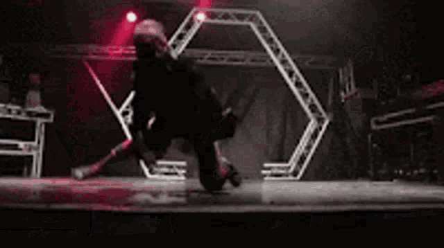 a person is dancing on a stage in a dark room with red lights .