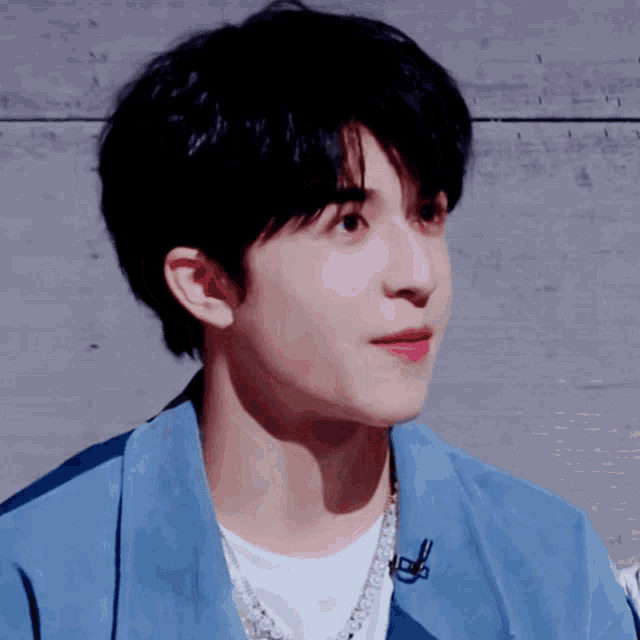 a close up of a young man wearing a blue shirt and a white shirt