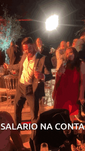 a man in a suit is dancing with a glass of wine and the words salario na conta are below him