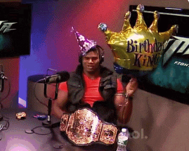 a man holding a birthday king balloon in front of a microphone