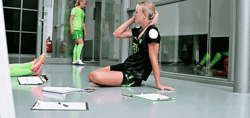 a female soccer player is sitting on the floor with a clipboard on the floor